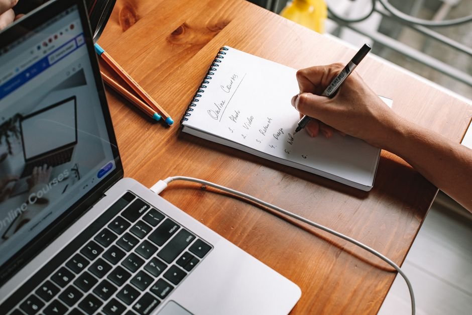 Professional writing notes while learning on a laptop - the 90-day AI skills plan for database professionals