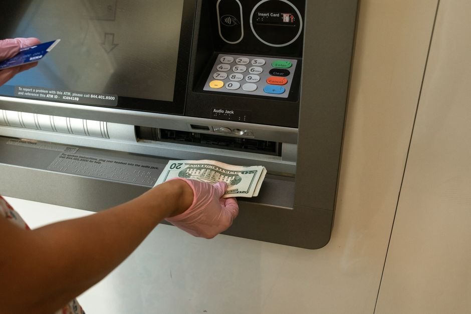 ATM-এ কার্ড ব্যবহার করছেন একজন গ্রাহক — প্রতিটি সোয়াইপ একেকটি OLTP ট্রানজেকশন, যা ব্যাংকিং Oracle ডেটাবেজকে মিলিসেকেন্ডে commit করতে হয়