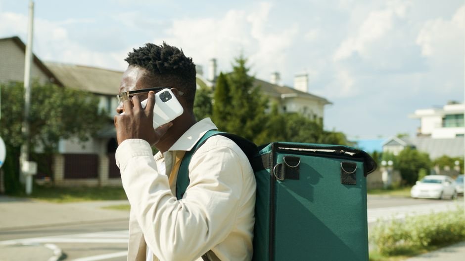 Courier delivering a package while the customer tracks the delivery update on WhatsApp