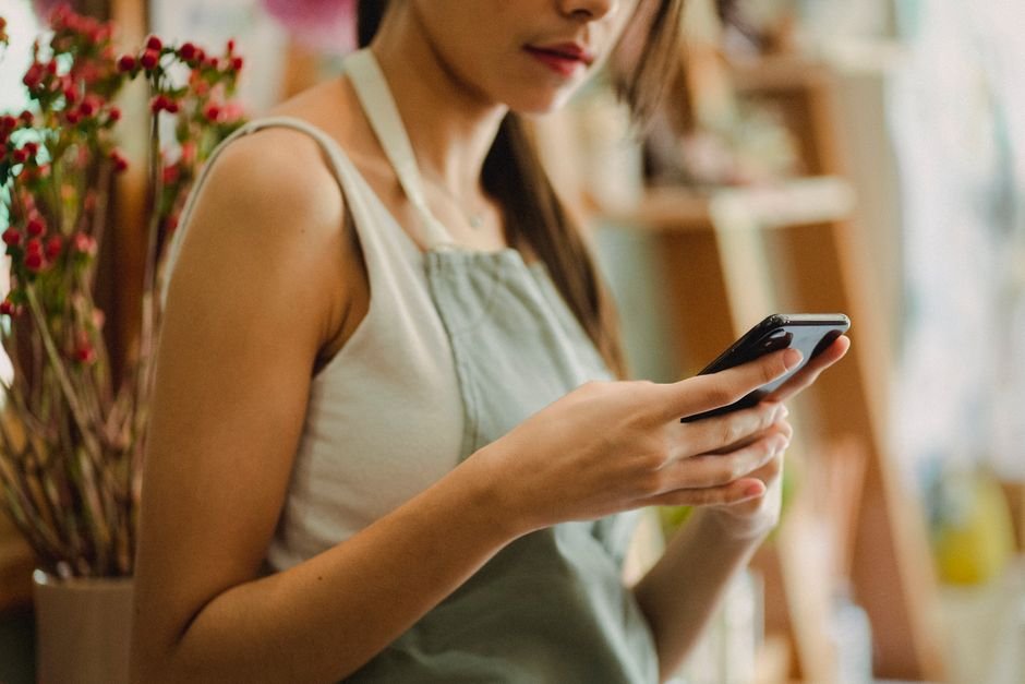 Small business owner replying to customer messages on WhatsApp from her shop